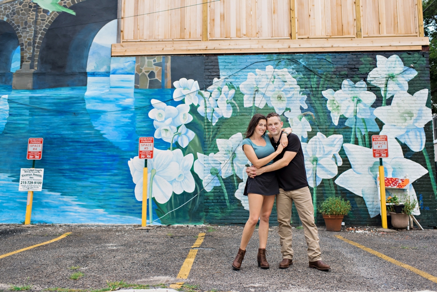 A couple hold each other in front of a flower mural in Philly.